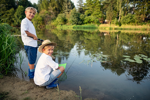 Happy boy aged 10 fishing in river\nNikon D850