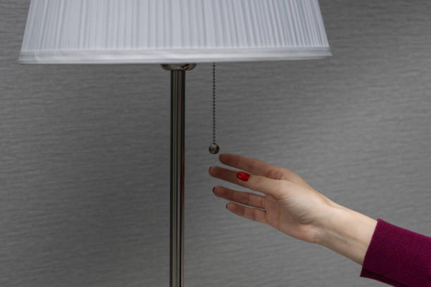 istock a woman turns on a floor lamp by pulling the switch chain 1390708201