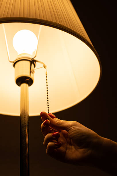 istock woman pulling the switch chain of a floor glowing lamp 1390708349