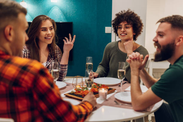 istock Group of friends enjoying dinner while sitting at the kitchen table together 1390710649
