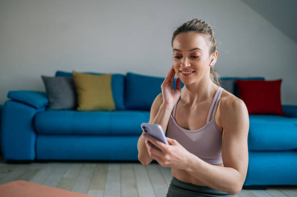 istock Woman using airpods and a smartphone while training at home 1390710655