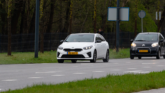 Enschede, Twente, Overijssel, Netherlands, april 5th 2022, close-up of a Dutch white 2019 KIA 3rd generation Ceed along with a black 2011 Citroen C1 approaching on the 'Hengelosestraat' in Enschede on a rainy day - the Proceed is a 5-door shooting brake version of the Ceed that is made by Korean, Seoul based Kia Corporation since 2006