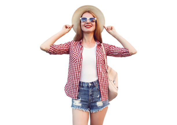 Portrait of young woman wearing summer straw hat, checkered shirt, shorts isolated on white background stock photo