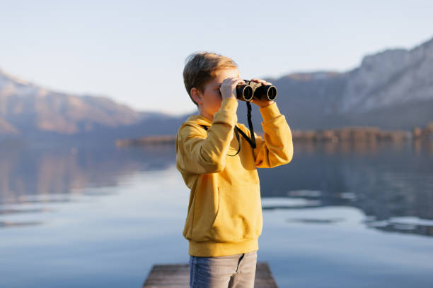 istock 8 years old boy looking through binoculars on the lake in mountains 1390715327