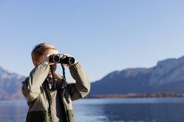 istock A boy looking through binoculars on the lake in mountains 1390716554