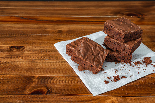 Stack of fresh chocolate brownie squares on a table. Copy space.