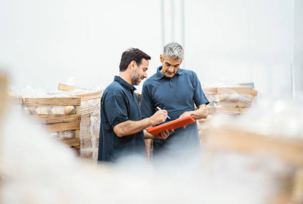 Mature workers taking inventory of packaged meat in the warehouse stock photo