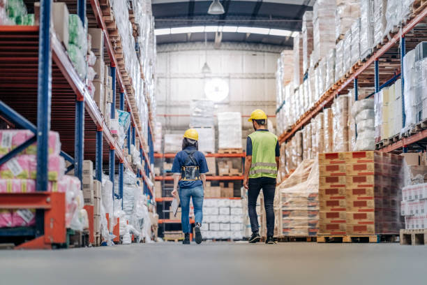 istock Rear view of two workers walking through a large distribution warehouse 1390717557