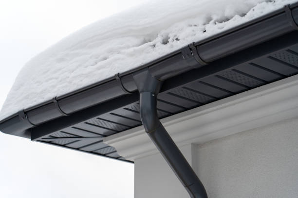istock Metal Downpipe system, Guttering System, External downpipes and drainage pipes under snow. Corner of house with roof made of gray metal tiles and gutter covered with thick layer of snow in winter. 1390717697