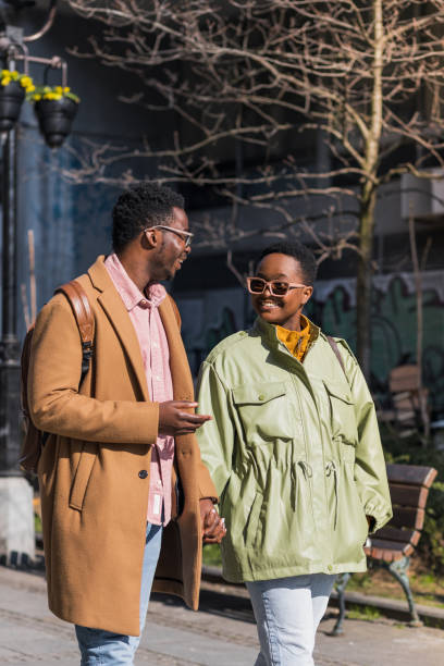 istock Smiling black couple holding hands while walking outside 1390720936