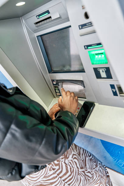 istock Lady using ATM machine to withdraw her money. Close-up of hand entering PIN or pass code on ATM bank machine keypad. Security code on Automated Teller Machine. 1390721406