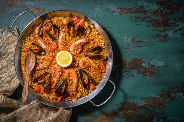 paella di pesce ricetta dieta mediterranea con gamberi, calamari e cozze su legno verde rustico - prepared shellfish foto e immagini stock