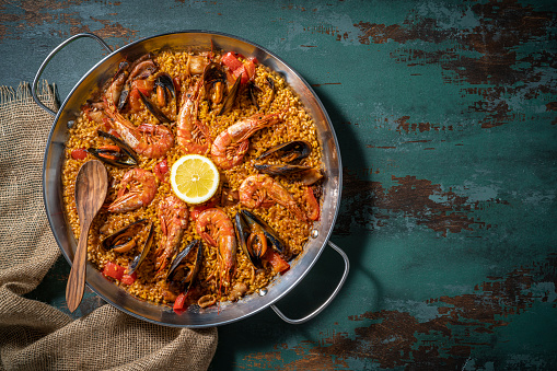 Seafood Paella Mediterranean diet recipe with shrimp, squid and mussels on rustic green wood