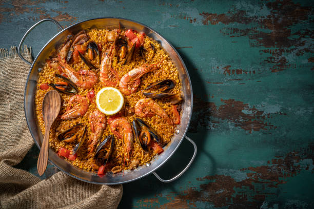 Seafood Paella Mediterranean diet recipe with shrimp, squid and mussels on rustic green wood Seafood Paella Mediterranean diet recipe with shrimp, squid and mussels on rustic green wooden background bivalve photos stock pictures, royalty-free photos & images