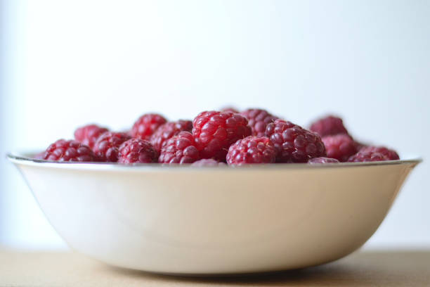 Front view of red raspberries in a porcelain bowl stock photo