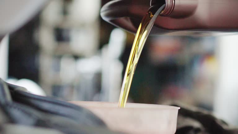 CU Man pouring motor oil to the Engine at Auto Repair Shop