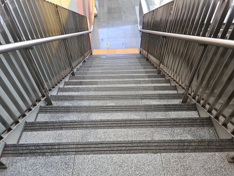 close up stairs made of gray ceramic and railing of stainless steel in one of the MRT train stations