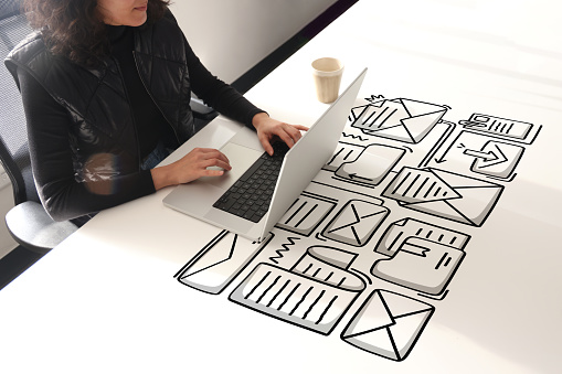Woman using laptop with envelope icons