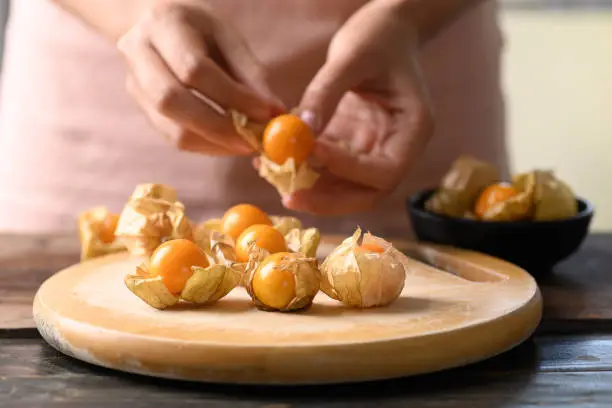 Cape gooseberry or golden berry (Physalis peruviana) holding by hand and prepare for eating, Healthy tropical fruit
