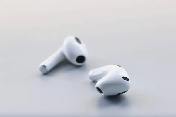 Photo of Pair of white wireless headphones on grey background, modern device to listen music or talk