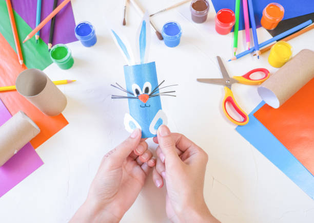 step 4. DIY paper rabbit from a roll of toilet paper. Easy craft for kids on white background, simple DIY idea from toilet tube, recycling concept. Gift ideas, decor for spring, Easter. Step by step. Crafts process. View from above. Children's Easter crafts paso 4. conejo de papel de bricolaje de un rollo de papel higiénico. manualidades fáciles para niños sobre fondo blanco, idea simple de bricolaje del tubo del inodoro, concepto de reciclaje. ideas de regalos, decoración para primavera, semana santa. pa