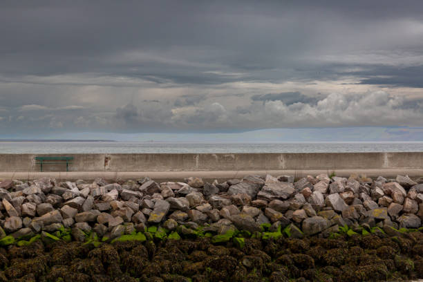 lonely bench at seawall on a natural stone shore