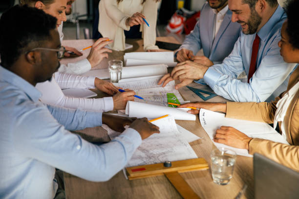 istock Diverse team of architects having a project meeting, analyzing blueprints 1390778205