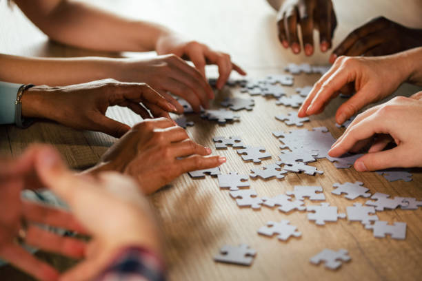istock Unrecognizable group of people assembling a jigsaw puzzle as a team 1390783355