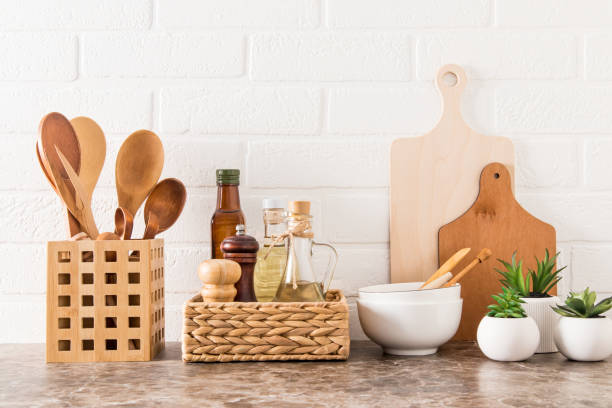 istock Stylish white kitchen background with kitchen utensils and green potted house plants on a marble countertop. 1390783479
