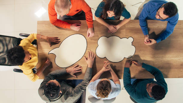 istock Business people sitting around thought bubbles on a conference table 1390784508
