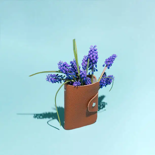 Photo of A purse from which purple flowers stick out.