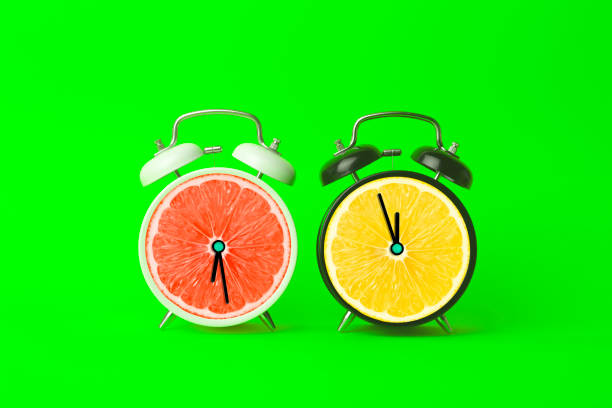 istock Alarm clocks with citrus fruit concept. Lemon or orange and clock on empty color background. Vitamins, proper nutrition, health, detox, diet concept. 1390785462