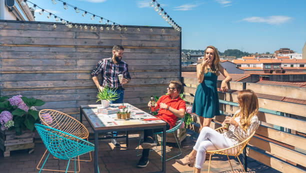 amigos hablando y bebiendo en una fiesta en una terraza - bancal fotografías e imágenes de stock