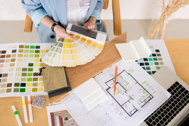 istock Woman architect working on interior renovation in workplace. Designer choosing color samples according to the visualization and blueprints of the project. Architecture and interior design concept. 1390787614