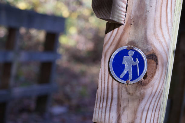 Close-up of a hiker symbol on the end of a bridge on a hiking trail in a park.