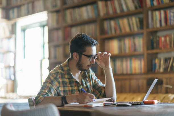 istock Young man studying with laptop at the library 1390788135