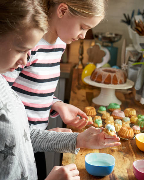 istock Two Girls Decorating Small Bundt Cakes with Sweets 1390788208