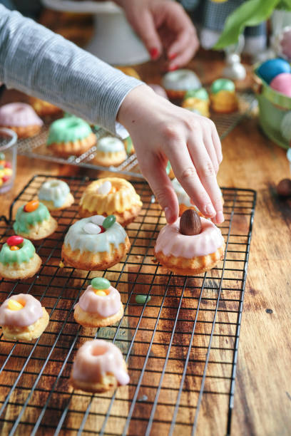 deux filles décorent de petits gâteaux bundt avec des bonbons - bunt photos et images de collection