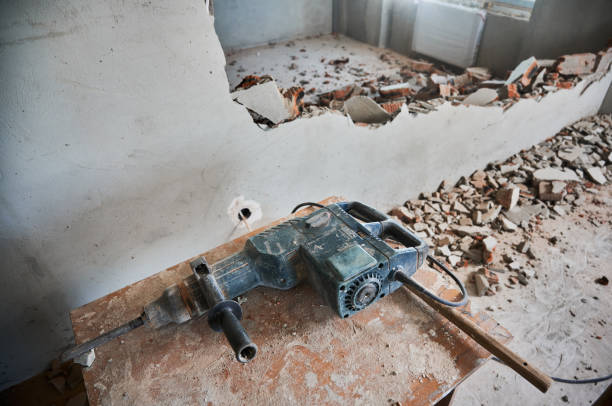 Wooden desk with electric hammer drill for construction and demolition works. Professional tool for demolishing and home renovation in room with destroyed wall.