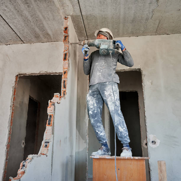 istock Male worker destroying wall between two rooms with hammer drill. 1390791365