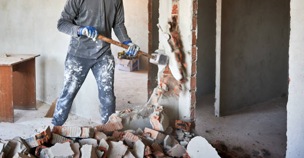 Cropped view dismantler crashing interroom septum with hand's large hammer. Close up of sledgehammer blow on brick, plaster. Workman striking devastating blow at remnants of interoom wall against backdrop of table and other plastered walls. demolished stock pictures, royalty-free photos & images