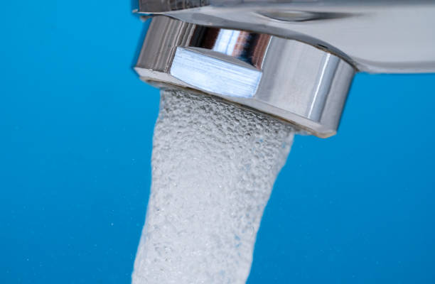 Closeup of clear running water from the tap against blue background