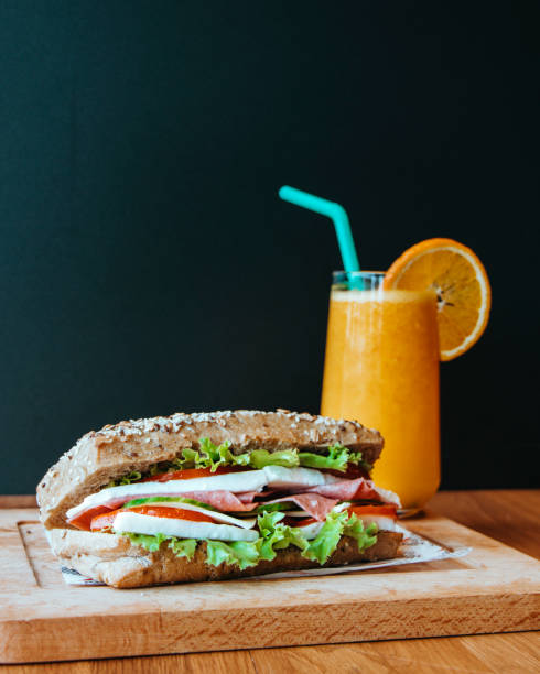 tomatenkäse und vegetarisches sandwich, sandwich und frisch gepresster orangensaft zum frühstück, sandwich und orangensaftservice im café - sandwich submarine sandwich ham bun stock-fotos und bilder