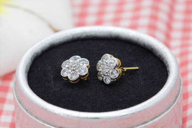 Beautiful golden earrings decorated with diamond in flower shape display in jewelry box Beautiful golden earrings decorated with diamond in flower shape display in jewelry box on red plaid cloth background jewelry box photos stock pictures, royalty-free photos & images