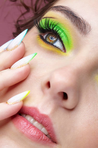 istock Young woman with green eyes makeup and multi-colored nails manicure. 1390793362