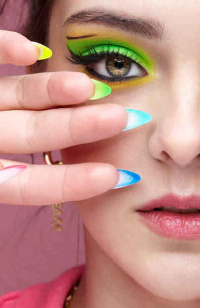 istock Young woman with green eyes makeup and multi-colored nails manicure. 1390793372
