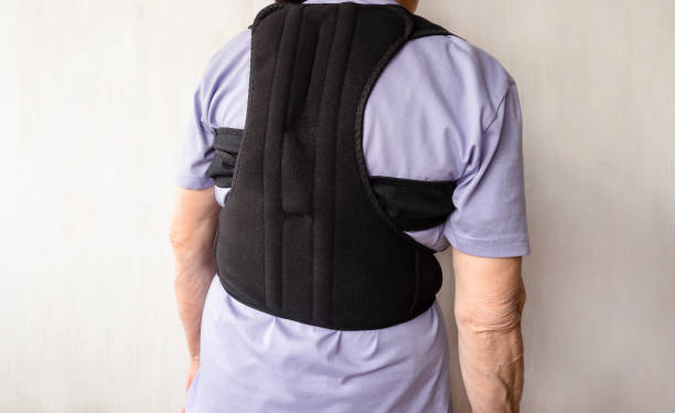 istock Orthopedic lumbar corset and back posture corrector. Posture corrector for the spine. Correction of scoliosis in an old woman. 1390796674