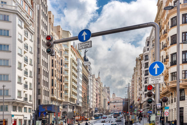 buildings and traffic in gran vía street, madrid. mid-day with clouds and clearings - avenue sign imagens e fotografias de stock