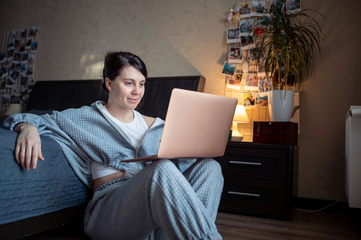 woman freelancer working at home on laptop sitting on the floor laptop knees