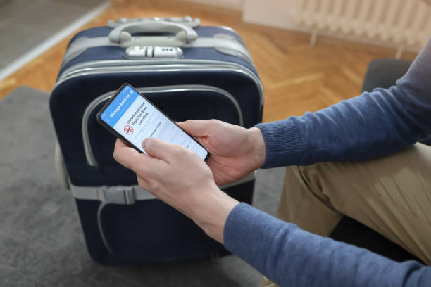 istock Man holding smart phone with flight cancelled on screen.
Flight Delayed notificationon Smartphone Screen. Man waiting in room with luggage. 1390800727